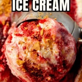A close-up of a scoop of no-churn strawberry cheesecake ice cream with swirls of strawberry sauce and chunks of graham cracker.