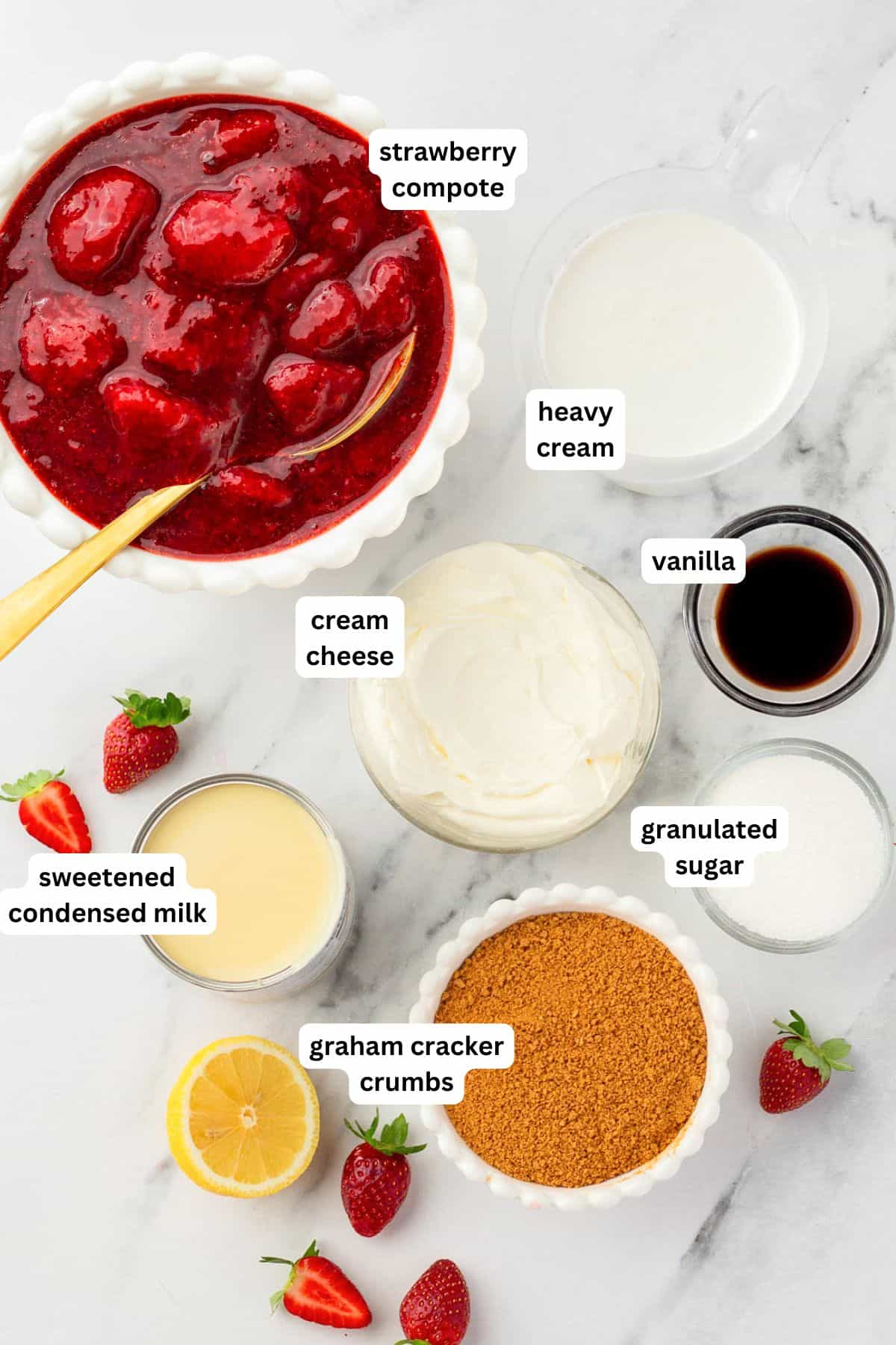 With no ice cream maker needed, this velvety Strawberry Cheesecake Ice Cream recipe has thick swirls of strawberry compote and graham cracker crumbs. A marble surface displays labeled ingredients for strawberry cheesecake ice cream in bowls: strawberry compote, heavy cream, vanilla, cream cheese, granulated sugar, sweetened condensed milk, and graham cracker crumbs.