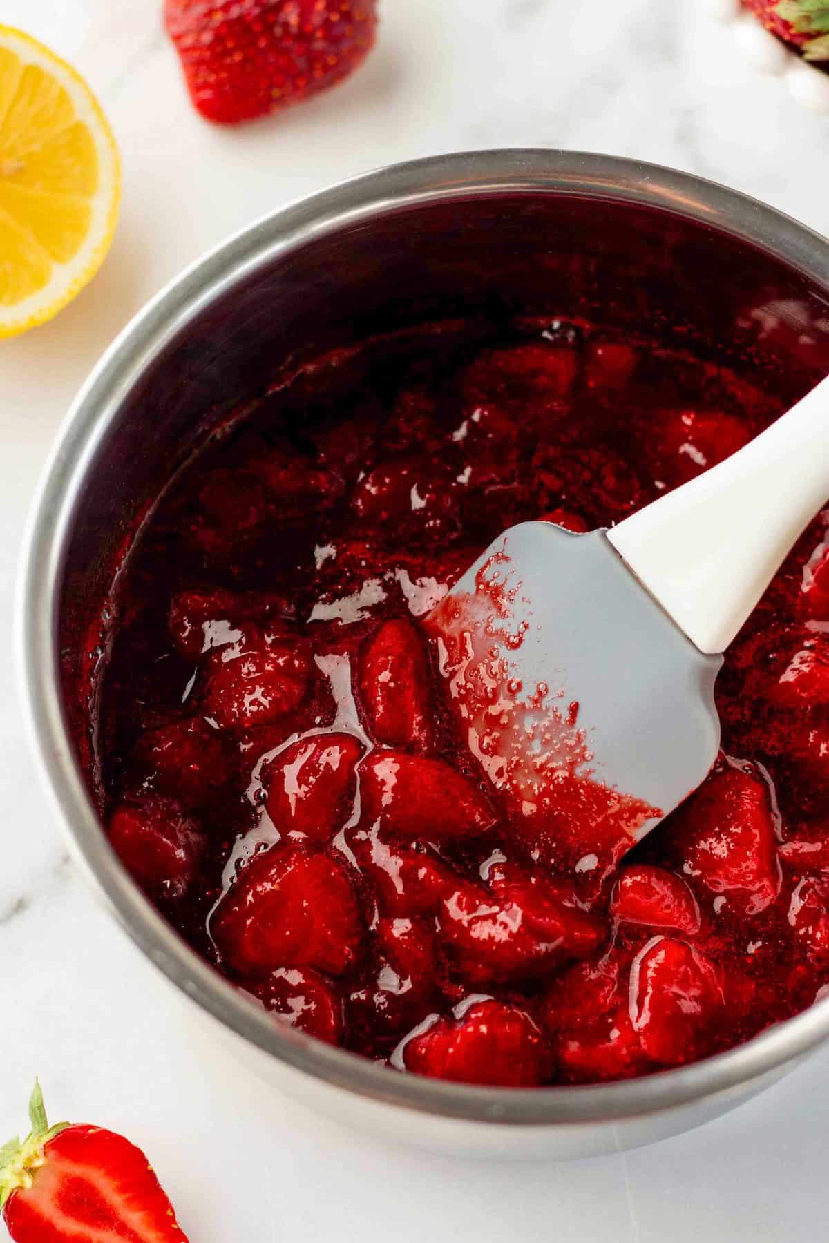 Made with only 4 ingredients in just 10 minutes, this homemade Strawberry Compote recipe is so thick and jammy - with no cornstarch needed! A saucepan filled with chunky fresh strawberry sauce being stirred with a white spatula.