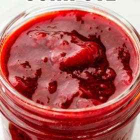 A glass jar filled with thick, red strawberry compote, seen from above.