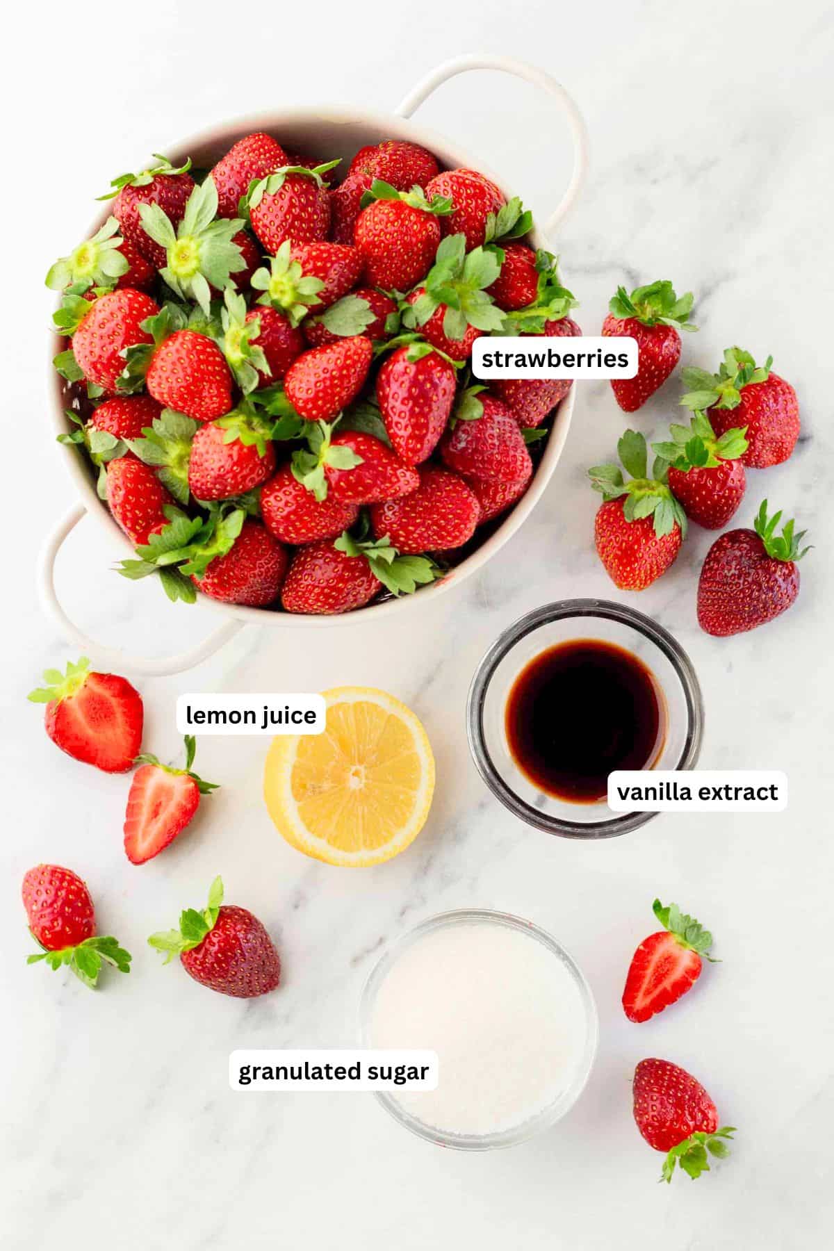 Made with only 4 ingredients in just 10 minutes, this homemade Strawberry Compote recipe is so thick and jammy - with no cornstarch needed! Labeled ingredients for strawberry compote recipe: a bowl of fresh strawberries, half a lemon, a small bowl of vanilla extract, a bowl of granulated sugar on a marble surface.