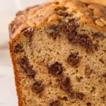 A close-up of a sliced loaf of chocolate chip peanut butter banana bread with slightly melted chocolate chips inside.
