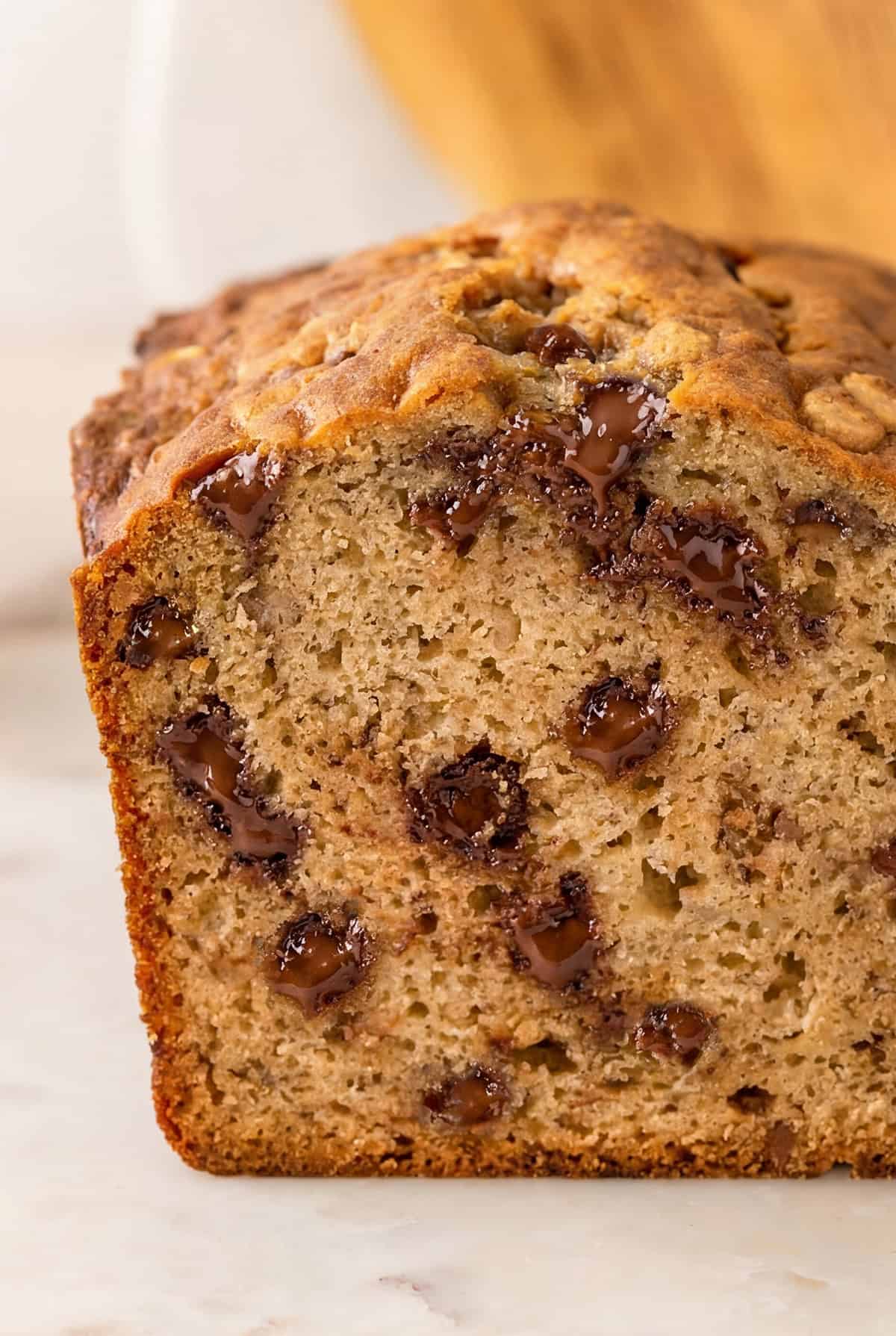 This Peanut Butter Banana Bread actually tastes like peanut butter! So soft, tender, and packed with both chocolate AND peanut butter chips. A close-up of a sliced loaf of chocolate chip peanut butter banana bread with slightly melted chocolate chips inside.