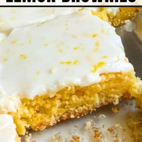 A close-up of chewy lemon brownies topped with glossy frosted icing, with one piece cut out and showing a moist, dense texture.