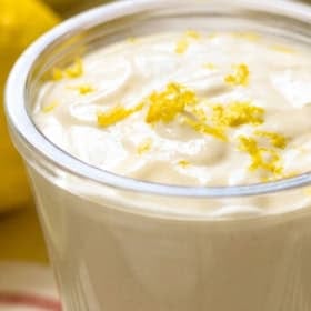 A small glass cup filled with creamy lemon aioli, topped with lemon zest. The text on the image reads Easy 5-Ingredient Lemon Aioli and The Novice Chef.