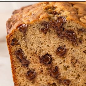 A close-up of a loaf of peanut butter chocolate chip banana bread with melted chocolate chips, showing a moist texture.