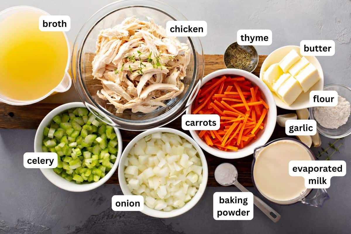 The best Chicken and Dumplings recipe you'll ever make! Ready in under an hour with a thick creamy broth, juicy chicken, and big fluffy dumplings. Overhead view of labeled ingredients for homemade chicken and dumplings recipe, including broth, shredded chicken, thyme, butter, flour, celery, carrots, onion, garlic, baking powder, and evaporated milk.