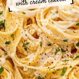 Close-up of creamy fettuccine Alfredo garnished with chopped parsley and black pepper. Text reads: Homemade Alfredo Sauce with cream cheese! Website source is thenovicechef.com.