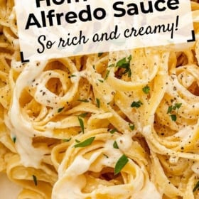 Close-up of fettuccine pasta coated in creamy Alfredo sauce, garnished with chopped parsley and cracked black pepper, with text overlay: Homemade Alfredo Sauce. So rich and creamy!.