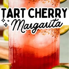 A glass of tart cherry margarita with a chili-lime rim, garnished with a lime slice and cherry, surrounded by lime wedges. Text: Tart Cherry Margarita and thenovicechef.com.