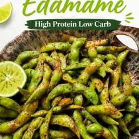 A rustic bowl filled with chili lime edamame, sprinkled with spices and garnished with lime slices.