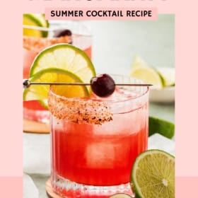 A glass of tart cherry margarita garnished with a lime slice and cherry, rimmed with spice, with ice and lime wedges nearby. Text reads: “Tart Cherry Margarita, Summer Cocktail Recipe, The Novice Chef.”.