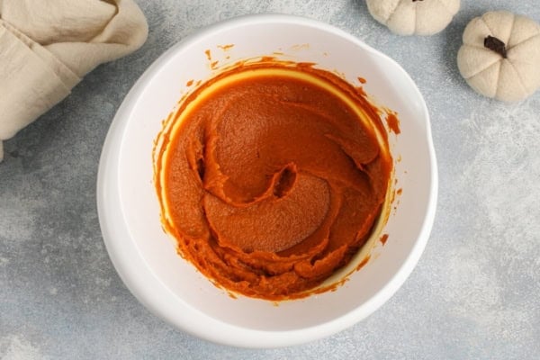 This no-bake Pumpkin Dip is perfectly spiced and made with marshmallow fluff to keep it extra fluffy. Party ready in just 5 minutes! A white bowl filled with smooth pumpkin puree mixed with seasonings.