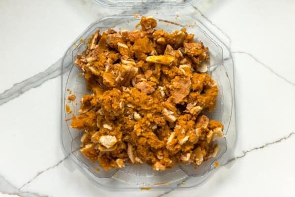 Pumpkin Pie Pudding layers a whole pumpkin pie with buttery graham crackers and the fluffiest pudding into the creamiest no-bake dessert! A crumbled pumpkin pie in a plastic pie container.