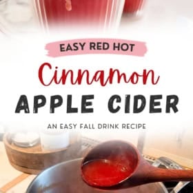 Two mugs of red hot apple cider topped with whipped cream and cinnamon, above a pot of cinnamon apple cider being stirred with a wooden ladle.